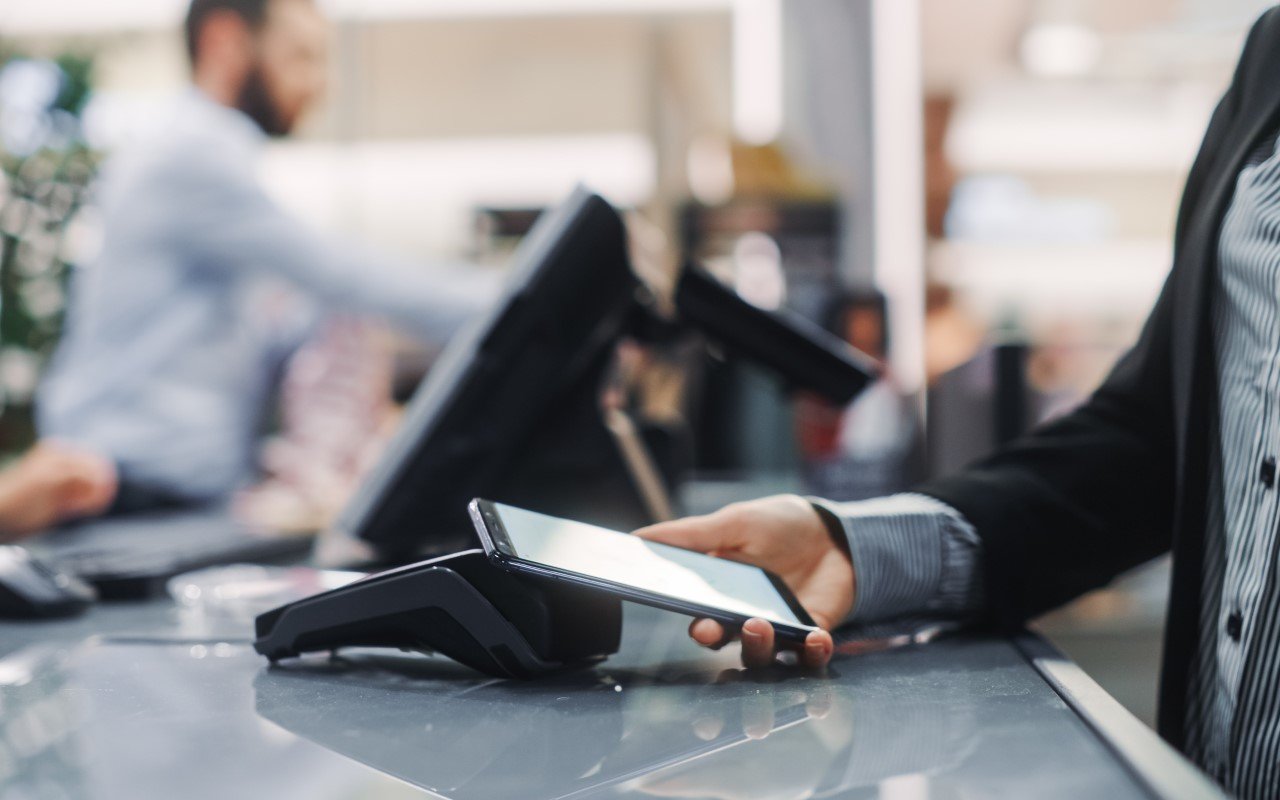 bilde av en person som bruker mobilen til betaling i terminal