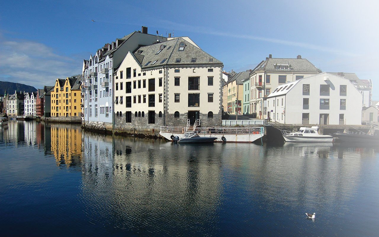 Bilde av Ålesund. Det er bygninger langs vannet.